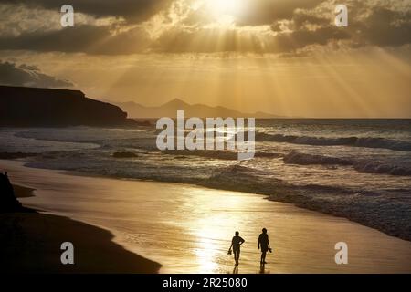Tramonto sulla spiaggia di la Pared, Fuerteventura - un uomo e una donna in piedi in sabbia illuminata Foto Stock