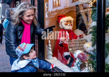 Un bambino e sua nonna guardano Un Christmas Shop Window Display, Sussex, Regno Unito Foto Stock