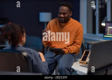 Coppia di programmatori che parlano tra loro mentre pranzano tardi in ufficio IT Foto Stock