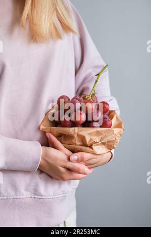 Mazzo di uve nelle mani di una ragazza. Closeup di uve mature raccolte a mano. Uve da vino rosso. Frutti di bosco freschi e succosi. Frutta dolce biologica sana Foto Stock