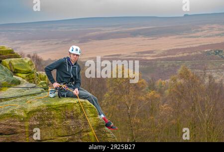 Adolescente rocciatore sul bordo di Birchen nel distretto di picco del Derbyshire Foto Stock