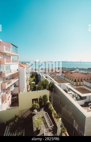 Lisbona; verticale; grandangolo; vista da un appartamento con una facciata color salmone alla città, che mostra il fiume Tejo e la replica del Golden Foto Stock