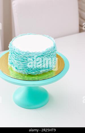 Squisita torta di compleanno decorata con volant verde e turchese su sfondo bianco Foto Stock