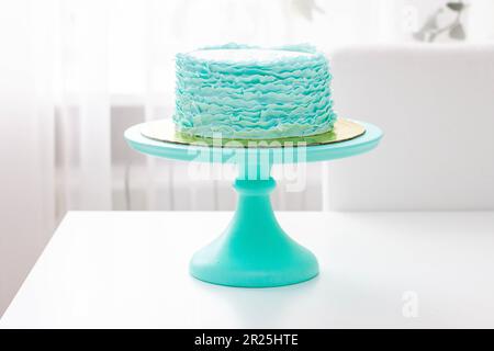 Squisita torta di compleanno decorata con volant verde e turchese su sfondo bianco Foto Stock