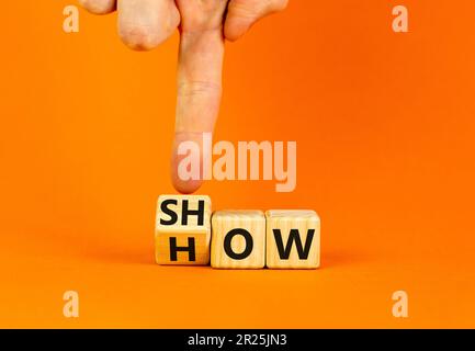Mostra come simbolo. L'uomo d'affari gira i cubi di legno e cambia la parola Mostra a come. Bella tavola arancione sfondo arancione. Spazio di copia. Business e S Foto Stock