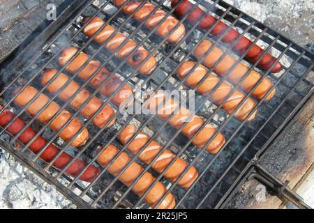 Le salsicce vengono fritte su una griglia metallica Foto Stock