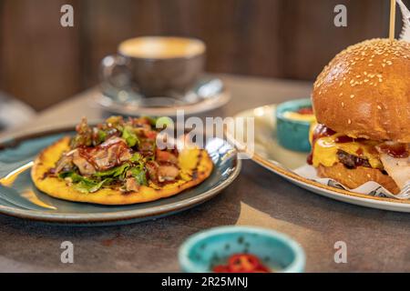 hamburger e kebab sul pane con salse servite al tavolo nel ristorante. Foto Stock