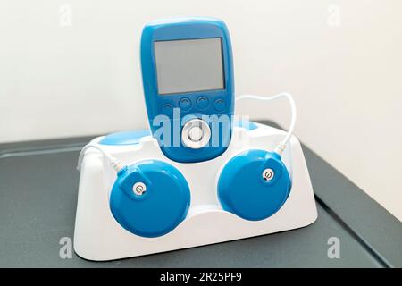 Closeup Blue Wireless elettrico Muscle Stimulator, trattamento del dolore su scaffale. Strumento di riabilitazione e formazione, attrezzatura. Concetto sanitario e medico Foto Stock