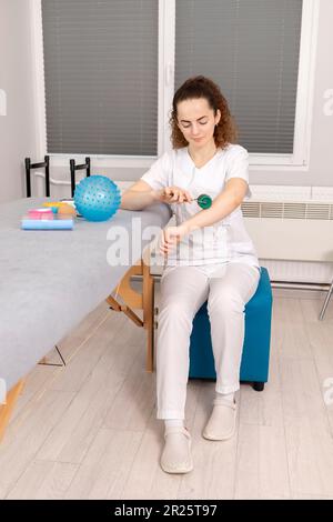 Specialista riabilitazione, fisioterapista con attrezzi Rehab, rullo in schiuma, palla da massaggio con pimples, Mesoroller con aghi in titanio, Cinesiologia Foto Stock