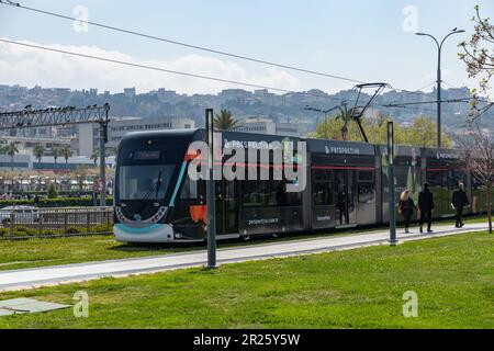 Un'immagine di un tram a Izmir a cavallo su piste witrh erba verde. Foto Stock