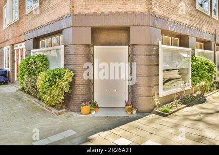 un edificio in mattoni con piante che crescono sul lato e una porta bianca aperta di fronte che conduce ad un parcheggio Foto Stock