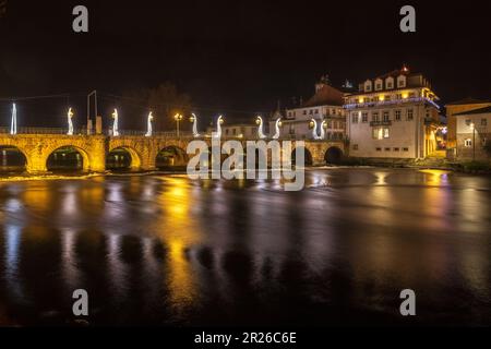 Vista notturna del ponte romano di Traiano sul fiume Tâmega nella città di Chaves in Portogallo, con luci natalizie. Foto Stock
