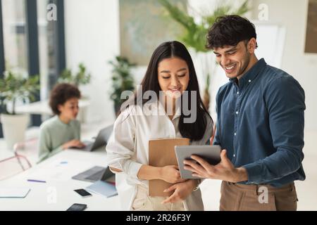 Due colleghi che utilizzano Tablet per discutere le idee in Office, godendo del lavoro di squadra Foto Stock