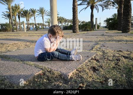 Il ragazzino caduto nel parco. sta piangendo. chiama per assistenza. Foto Stock