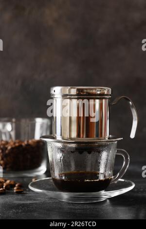 Metodo tradizionale di preparazione del caffè vietnamita con latte condensato su fondo nero. Primo piano. Formato verticale. Foto Stock