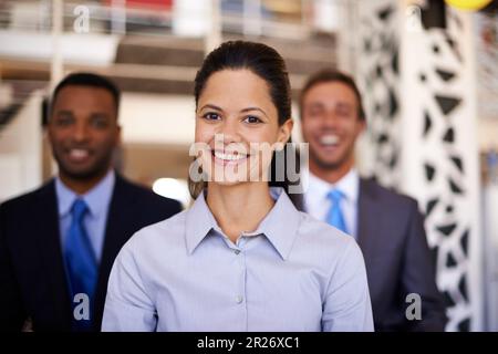 Fornisce un bene prezioso a questa azienda. Ritratto di una donna d'affari attraente con i suoi colleghi sullo sfondo. Foto Stock