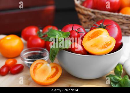 Diversi tipi di pomodori con basilico su tavola di legno Foto Stock