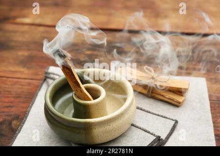 Bastone di palo Santo che frolla in supporto su tavolo di legno Foto Stock