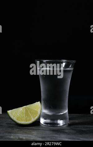 Colpo di vodka con fettina di lime sul tavolo grigio Foto Stock