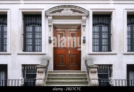 Edificio di appartamenti o entrata di una casa cittadina con un design in pietra ornata ed elegante porta frontale in legno intagliato Foto Stock