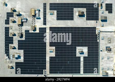 Vista aerea della centrale solare con pannelli fotovoltaici blu montati sul tetto dell'edificio industriale per la produzione di elettricità ecologica verde Foto Stock