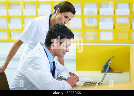 Ottenere una seconda opinione. un bel giovane medico e il suo assistente infermieristico che guarda lo schermo di un computer portatile. Foto Stock