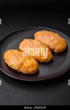 Deliziose cotolette di vapore con carote, formaggio, sale e spezie su fondo di cemento scuro Foto Stock