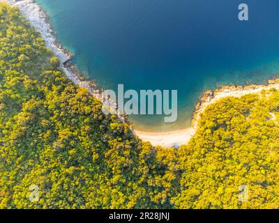 Scogliere rocciose con piccola spiaggia e mare blu nei giorni estivi soleggiati. Istria costa adriatica, Croazia Foto Stock