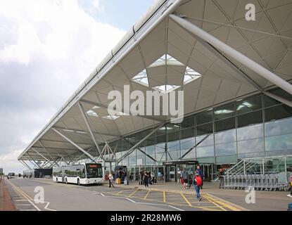Aeroporto di Stansted, Regno Unito. Un autobus navetta per il parcheggio fa scendere i passeggeri di fronte all'edificio principale del terminal Foto Stock
