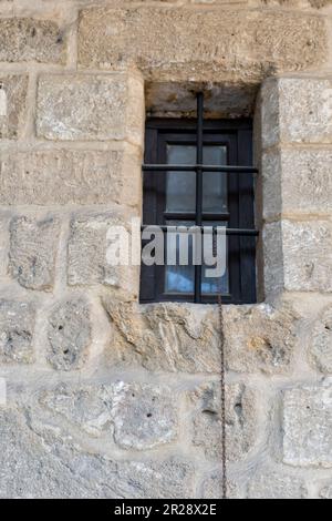 Una finestra con barre di ferro in vecchio muro di pietra di Buyuk Han (Great Inn) a Nicosia, Cipro del Nord. Foto Stock