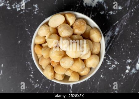 Noci di macadamia. Noci di Macadamia sbucciate in un recipiente di ceramica. supercibo. Cucina vegetariana. spuntini salutari. Vista dall'alto Foto Stock