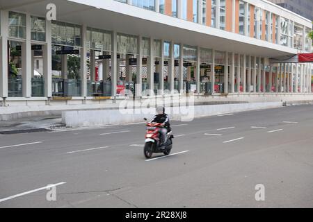 Autista ciclomotore nella vuota strada di Giacarta. Foto Stock