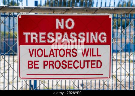Cartello "No Trespassing - i violatori saranno perseguiti" sulla recinzione metallica. Cantiere e soleggiato Foto Stock