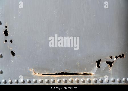 Primo piano del vecchio metallo arrugginito con rivetti e fori Foto Stock