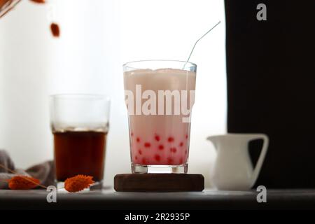 Tè fatto in casa con bolle di latte e perle di tapioca. Bevanda ghiacciata con tè al latte di fragola e palline di tapioca. Bevanda lattea con bolle di tapioka e ghiaccio Foto Stock