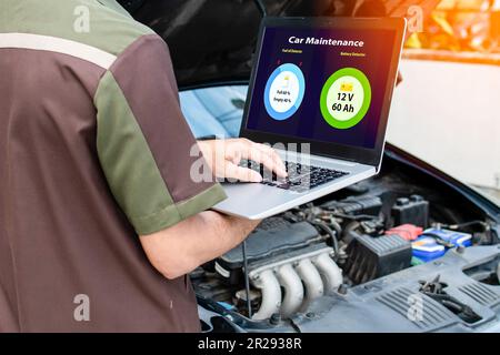 Primo piano, mano dell'uomo che digita sulla tastiera del computer portatile per controllare il funzionamento del motore dell'auto nel garage. Il motore di una vettura non si avvia. No Foto Stock