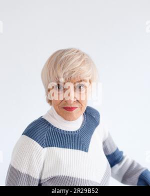 Studio ritratto di una donna anziana. Un modello più vecchio con capelli corti grigi. Fotografia di moda in studio. Ritratto sicuro di sé di una donna anziana Foto Stock