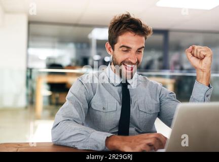 Uomo d'affari, pugno e festeggia con il notebook, vincendo e promovendo all'avvio con il volto eccitato. Giovane uomo d'affari, vincitore e festa con Foto Stock
