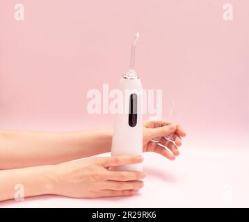 Irrigatore per denti orali con beccuccio, detergente per denti per acqua dentale, interdentale portatile bianco senza filo su sfondo rosa Foto Stock