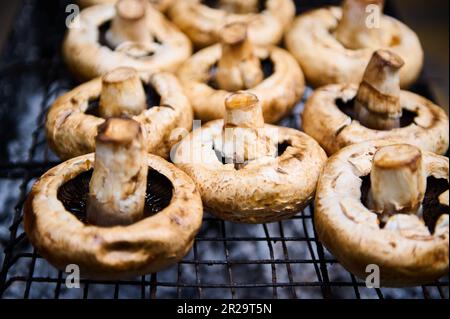 Vista ravvicinata dei funghi porcini marinati marinati marinati e stagionati, cucinati su una griglia a carbone fiammeggiante Foto Stock