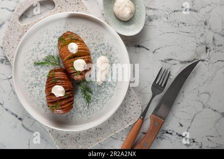 Patate al forno servite con erbe e salsa. Foto Stock