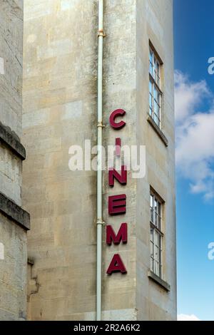 Vista verticale della facciata di un edificio in pietra arenaria con finestre e sul lato con lettere rosse che indicano la presenza di un cinema Foto Stock