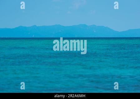 Mare blu intenso con un'isola montuosa all'orizzonte. Una vista di Ko Adang dall'Isola di KLA vicino a Ko Lipe, Thailandia. Foto Stock
