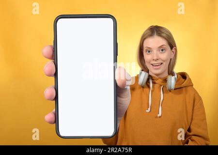 donna simpatica che mostra lo smartphone con schermo bianco vuoto Foto Stock