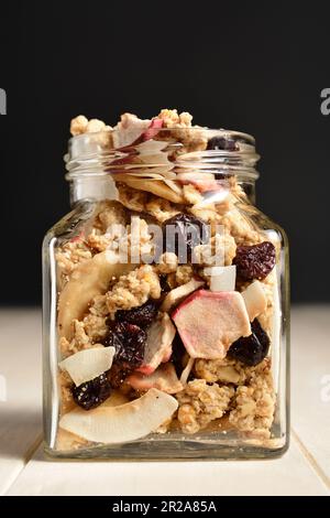 Deliziosa colazione muesli con cocco secco, banana, mela, mirtilli rossi e uva passa. Foto Stock