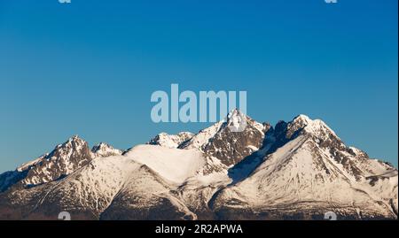 Montagne innevate che si innevano sotto il cielo blu Foto Stock