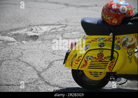Vespa d'epoca su misura con casco dipinto a mano e decorata con iconografia popolare siciliana in Sicilia, Italia. Foto Stock