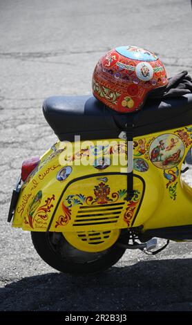 Vespa d'epoca su misura con casco dipinto a mano e decorata con iconografia popolare siciliana in Sicilia, Italia. Foto Stock