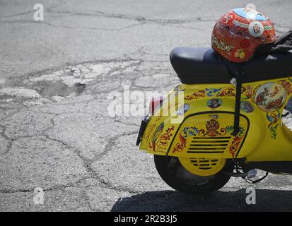 Vespa d'epoca su misura con casco dipinto a mano e decorata con iconografia popolare siciliana in Sicilia, Italia. Foto Stock