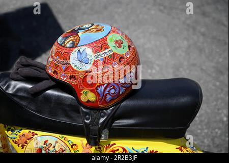 Vespa d'epoca su misura con casco dipinto a mano e decorata con iconografia popolare siciliana in Sicilia, Italia. Foto Stock